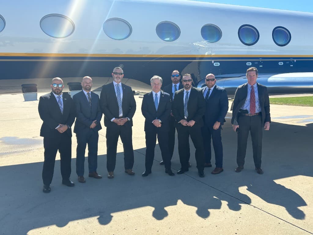 Rob Gunderson with a protective detail standing in front of an aircraft with the FBI Deputy Director