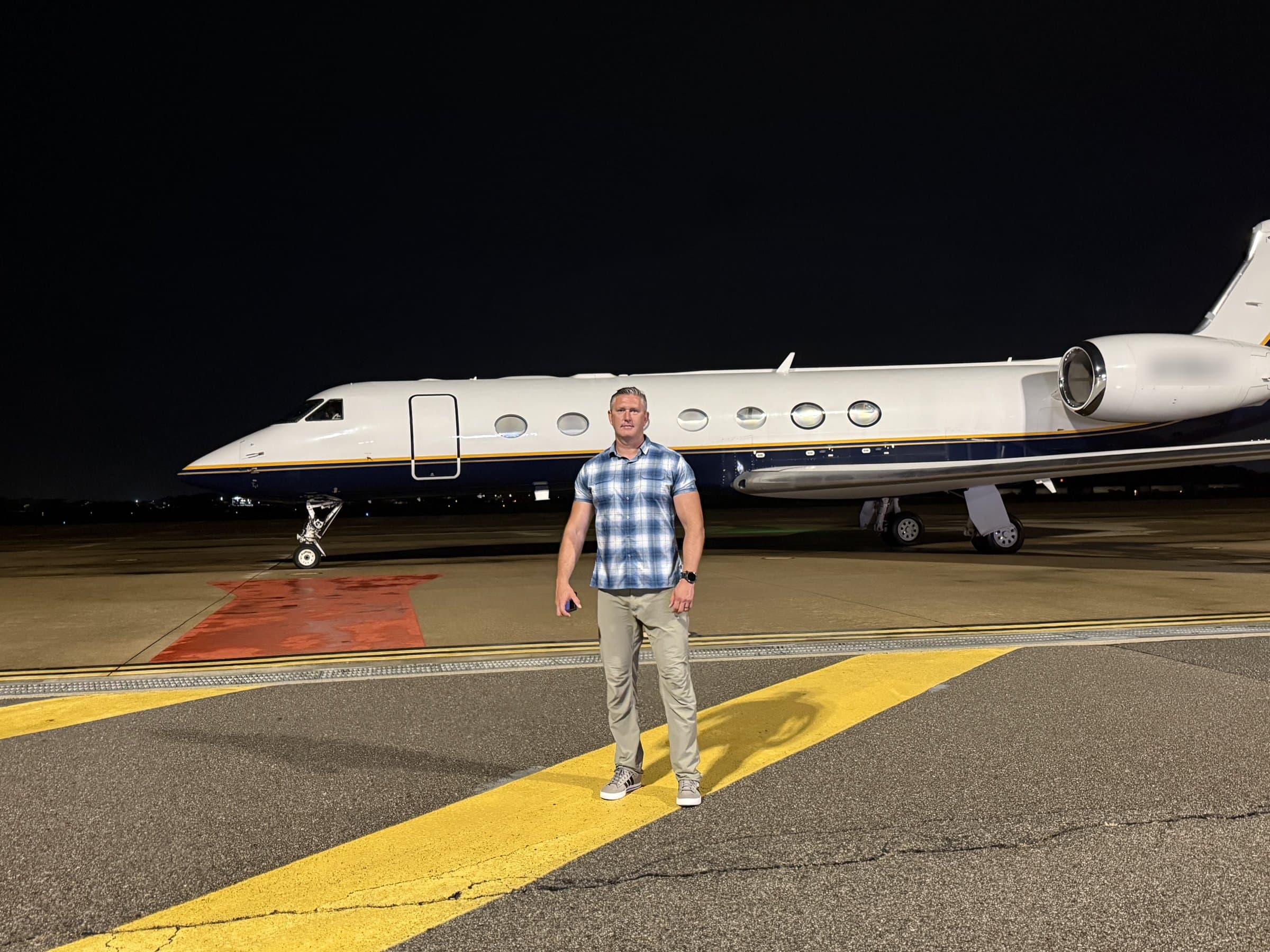 Rob Gunderson standing on a runway at night in front of a private jet