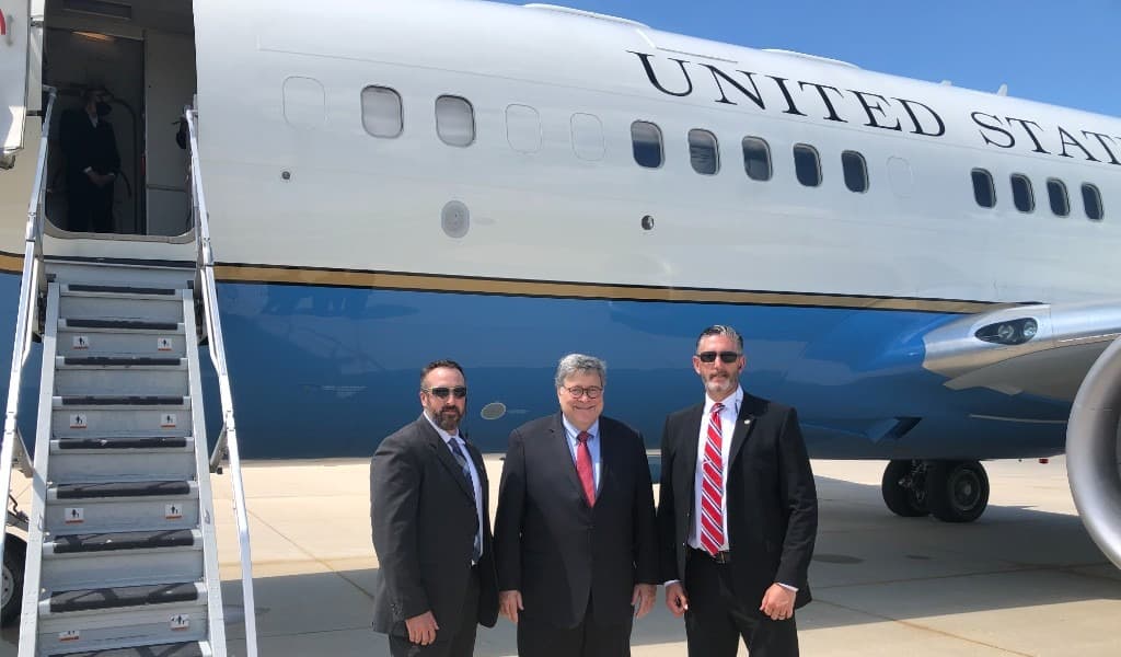 Rob Gunderson standing on a tarmac with a protective detail beside a United States aircraft
